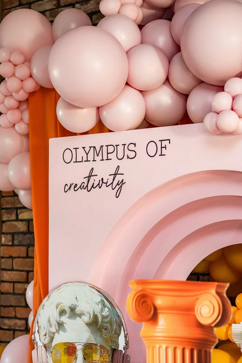 Detal scenografii — kolumny, złoty hełm i pastelowe balony
